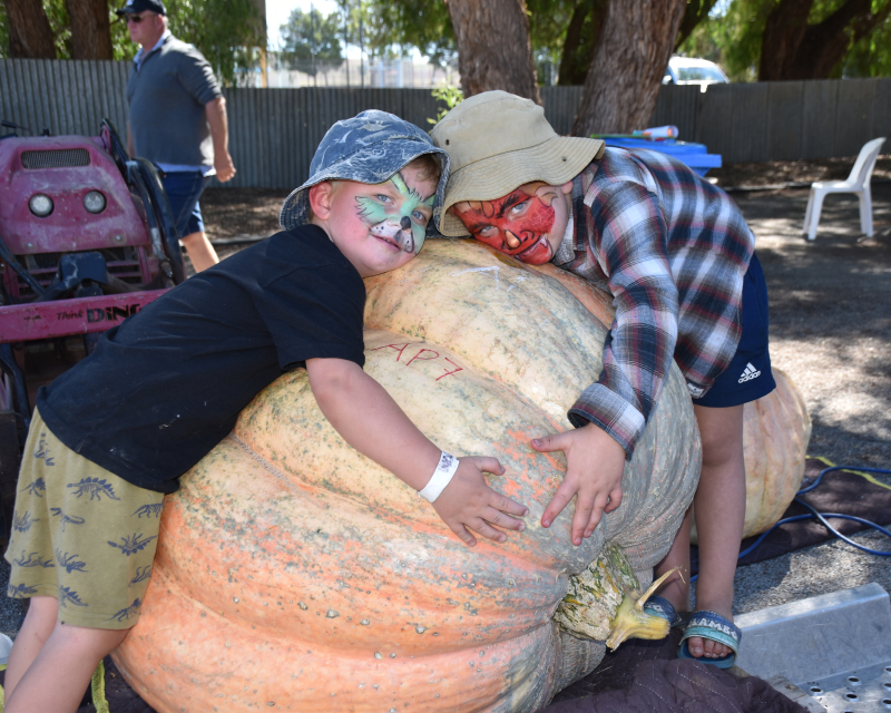 A gigantic pumpkin with two children in face paint