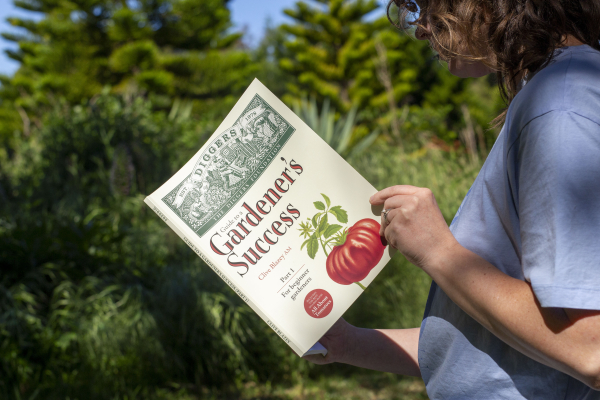 A woman reads a book titled A Guide to Gardener's Success: Part 1